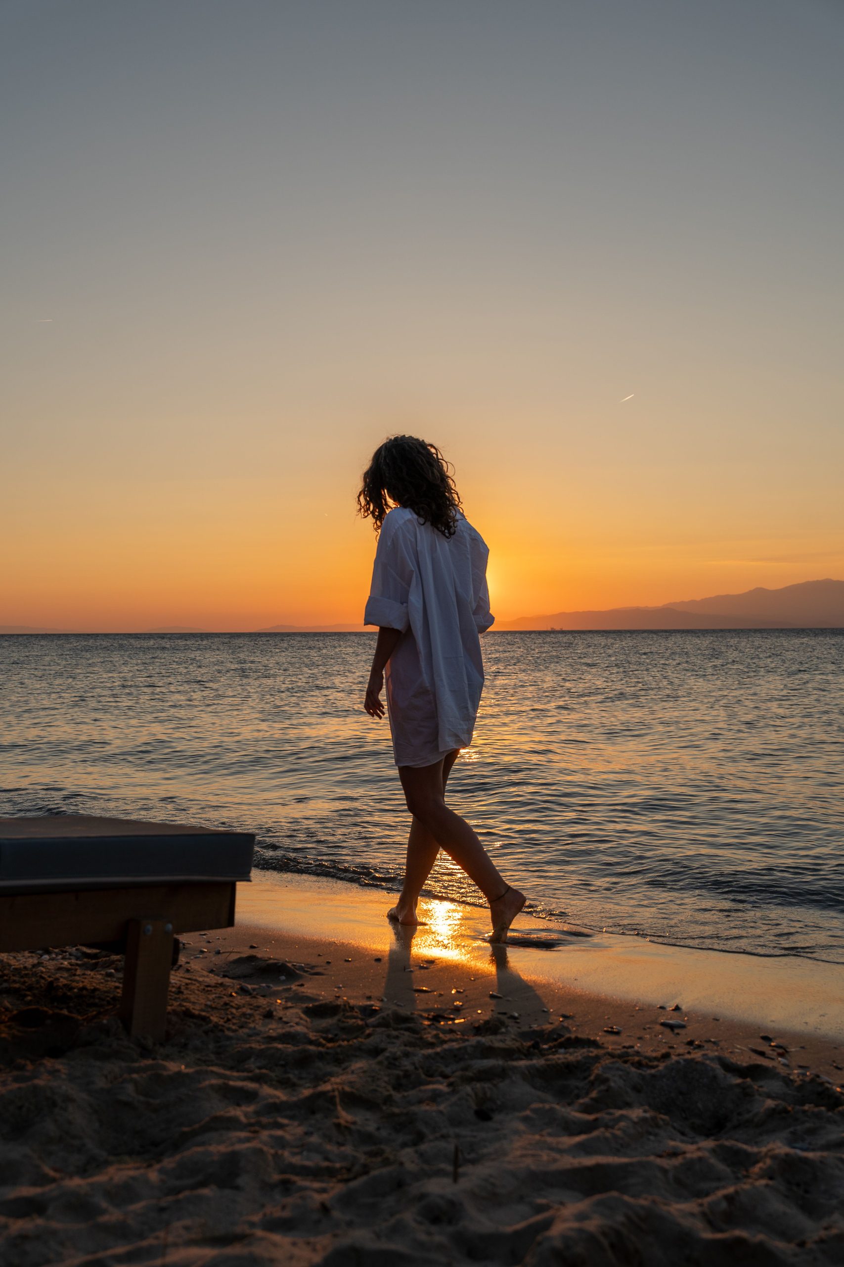 Woman walking on the beach at sunset — reflecting on things I wish I knew in my 20s